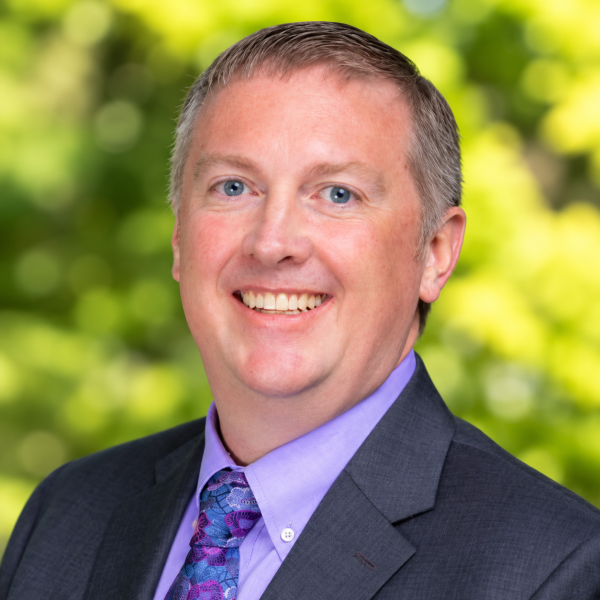 Headshot of Brett Rowlett with green background